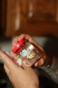 a person holding a glass jar filled with magnets on their thumbnails and using a cell phone