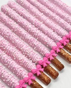 pink and white candy sticks are lined up in a row, with bows on them