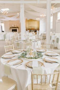 the tables are set with white linens and gold chargers