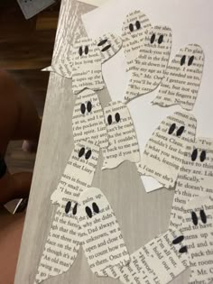 paper cut out to look like ghost faces on a piece of book page with scissors