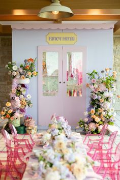 a table set up for a party with pink chairs and flowers on the tables in front of it