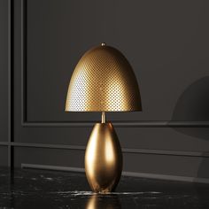 a gold lamp sitting on top of a black table next to a wall and floor