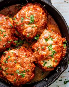 meatballs in a skillet with cheese and parsley on top, ready to be eaten