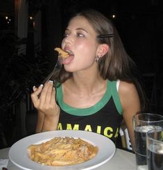 a woman eating food from a white plate