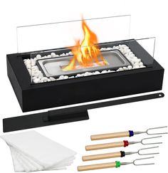 an outdoor fire pit with four tongs and two napkins next to the flame