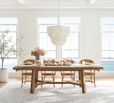 a dining room table and chairs in front of large windows with ocean view behind them