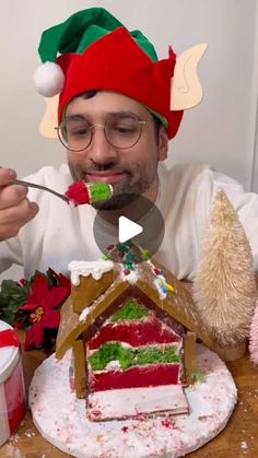 a man in a santa hat eating a slice of gingerbread house with a fork