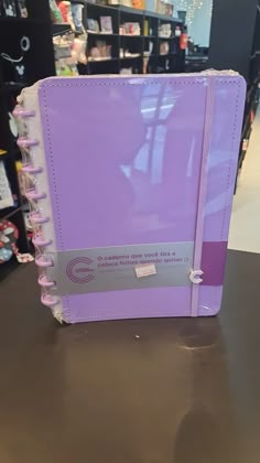 a purple binder sitting on top of a table in a store with other items behind it