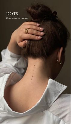 the back of a woman's head with dots on her neck and hand behind her ear