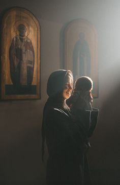 two women are standing in front of paintings and one is holding her face to the other side