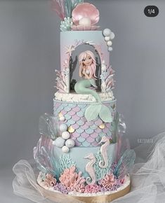 a three tiered cake decorated with an image of a mermaid and seahorse on it