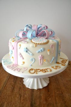 a white cake with pink, blue and gold decorations on it sitting on a table