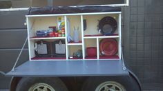 the back end of a truck with many items on it's shelf and wheels