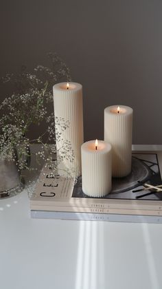 three white candles sitting on top of a book