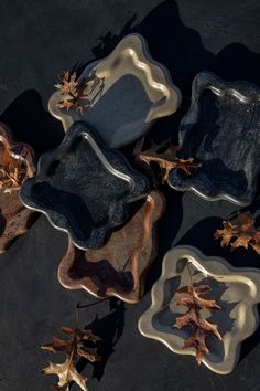 four glass plates with leaves on them sitting on a black table top next to each other