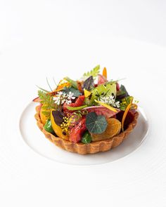 a white plate topped with a colorful fruit and vegetable tartillte on top of it