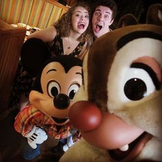 two people are posing with goofy and pluto the dog mascot in front of their faces