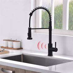 a kitchen sink with black faucet and pull out sprayer on the side