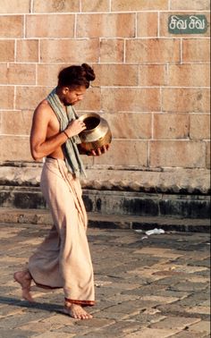 a man walking down the street with a bowl in his hand