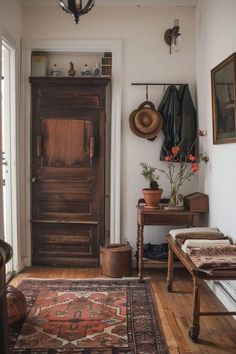 a room with a wooden door and rugs on the floor next to an old table