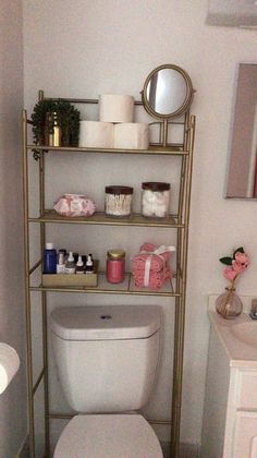 a white toilet sitting under a bathroom mirror next to a shelf filled with candles and other items