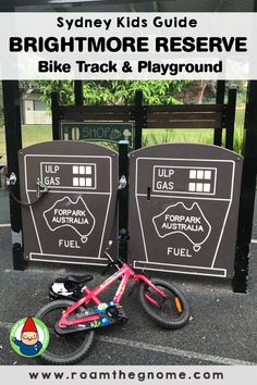 a pink bike parked next to a black sign with information about the park and playground