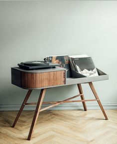 a record player on a wooden table with vinyl records in front of it's turntable