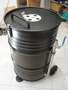 a large black barrel sitting on top of a white tile floor