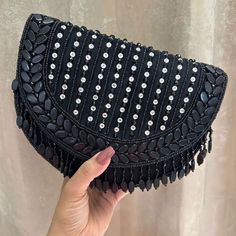 Introducing the Black Shefali Flap Bag, a stunning fusion of elegance and Indian craftsmanship. Hand-beaded with luxurious velvet in enchanting hues of Black, this bag embodies opulence and tradition. Its intricate design, coupled with delicate Black bead work, this makes it a standout accessory for brides and lovers of Indian fashion alike. Whether for a wedding ceremony or a cultural celebration, the Shefali Black Flap Bag adds a touch of regal charm to any outfit. Elevate your ensemble with the exquisite beauty of this Indian-inspired bridal bag. Materials used: Suede, Beading, Gold plated hardware At Romikas, we pride ourselves on the craftsmanship and high quality of our jewelry, designed to enhance your natural beauty. Please contact us with any questions. Luxury Black Beaded Evening Bag, Hand Embellished Black Evening Bag, Black Hand Embellished Evening Bag, Elegant Hand Embellished Black Bag, Elegant Black Hand-embellished Bag, Elegant Black Hand-embellished Clutch, Elegant Black Hand Embellished Clutch, Traditional Beaded Clutch Bag, Luxury Hand-embellished Black Evening Bag