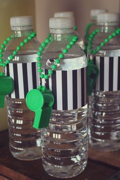 some water bottles are decorated with green and white stripes, one has a green plastic key on it