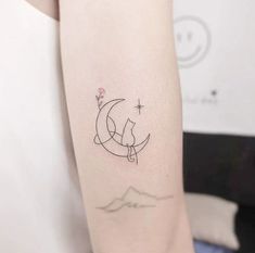 a cat sitting on the moon tattoo on the right arm and shoulder, with stars in the sky above it