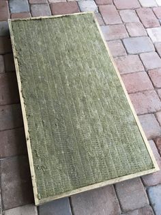 a piece of wood sitting on top of a brick floor next to a white dog