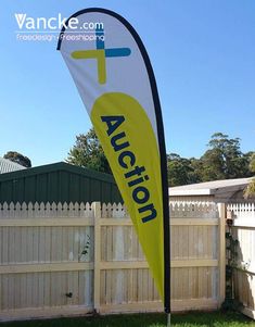 an auction sign in front of a white picket fence with a blue sky behind it