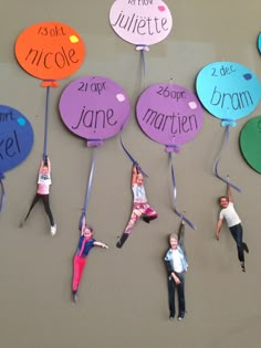 some people are hanging on the wall with their name tags attached to them and one person is upside down