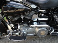 the front end of a black motorcycle parked on top of a street next to grass