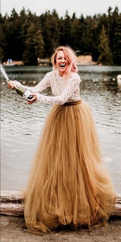 a woman in a long skirt is standing by the water