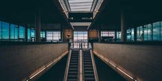 an escalator leading up to the top floor in a building with windows on both sides