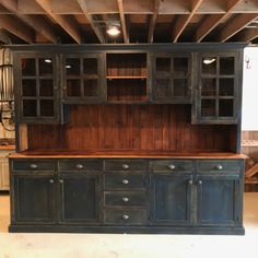 an old wooden cabinet with glass doors and drawers in a warehouse or workshop, ready for remodeling