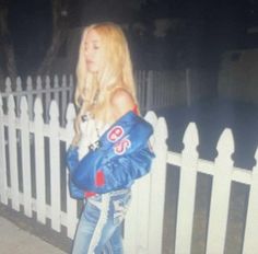 a woman is standing in front of a white fence