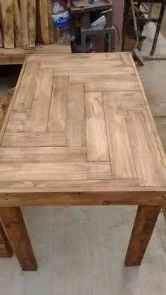 a wooden table sitting on top of a floor next to a pile of pallets