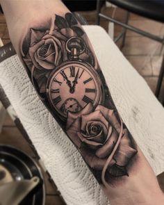 a clock and roses tattoo on the arm