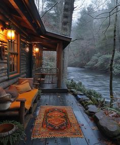 a porch with a rug on the floor next to a river and trees in the background