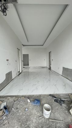 an empty room with white walls and paint buckets on the floor in front of it