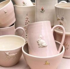 many cups and saucers are lined up on the table, one has a white bunny