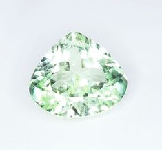 a pear shaped green diamond on a white surface with the center cut out to show it's lust