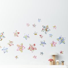 the wall is decorated with colorful flowers and butterflies on it's white walls, along with two small stools