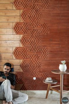 a man sitting on the floor in front of a wall that has geometric designs painted on it