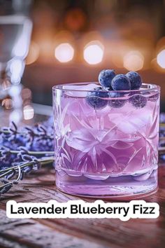 a glass filled with blueberries sitting on top of a table next to lavender flowers