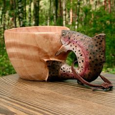 a wooden bowl sitting on top of a wooden table next to a small bird statue