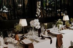 the table is set with white flowers and place settings